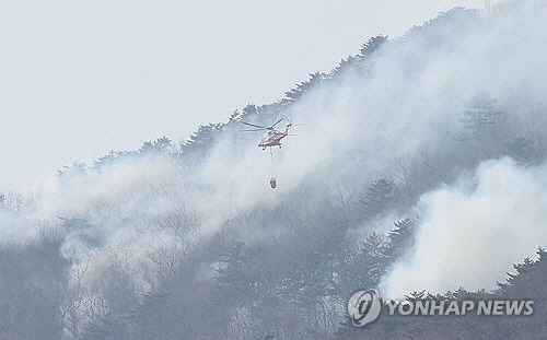울산시 울주군 온양읍 산불 사흘째인 24일 헬기가 화재 지점에 물을 뿌리기 위해 연기 속으로 접근하고 있다. [울산=연합뉴스]